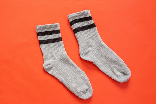 Grey socks isolated on red background. Top view of striped socks.