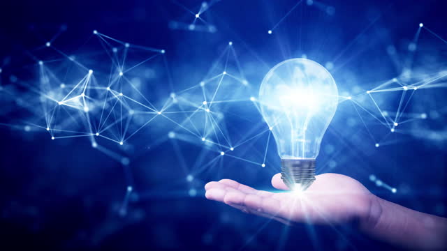 business idea creative concept technology. Illuminated light bulb and connected polygons above hand on dark blue background.