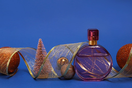 Christmas composition with pink perfume bottle on blue background