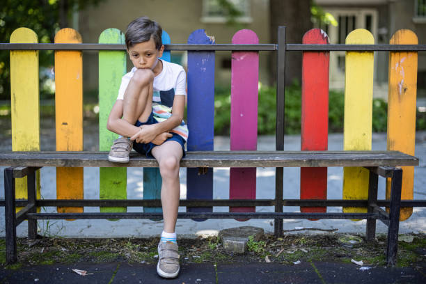 istock Kid sitting on a bench and feeling lonely 1443590225