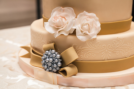 A beautiful wedding cake on a round table surrounded with fresh flowers. 