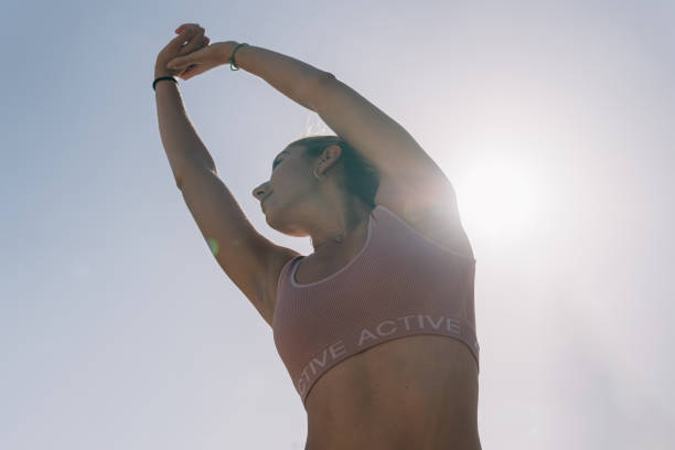 istock Athlete woman performing shoulder and back stretches while raising both joined hands into the air. 1443596993