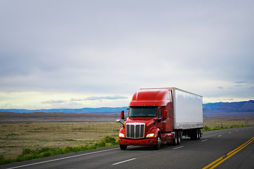 Red and white semi-truck driving in the  plains of Utah, USA