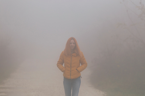 Woman walk outdoors on foggy autumn day