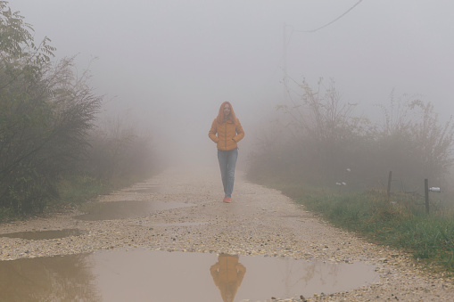 Woman walk outdoors on foggy autumn day