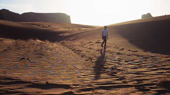 Native american girl walking among  the sand dunes of Monument Valley Utah