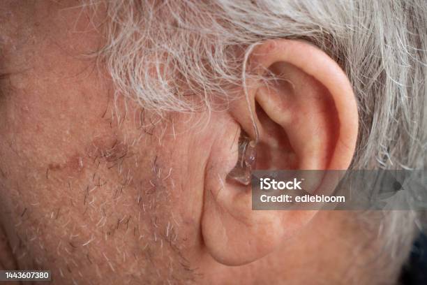 Hearing Aid Placed In The Ear Of An Elderly Person Stock Photo - Download Image Now - Ear, Senior Adult, Senior Men