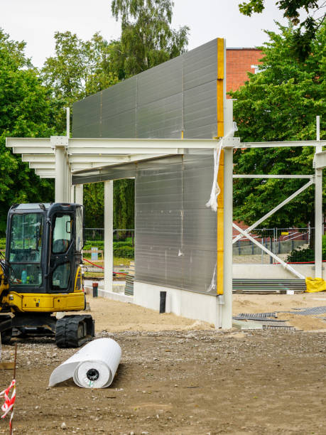 Unfinished steel construction frame of a new modern warehouse with gray sandwich panel wall Unfinished white prefabricated steel construction frame of a new modern warehouse with gray sandwich panel wall sandwich panel photos stock pictures, royalty-free photos & images