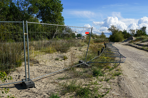 Partially overturned temporary steel portable fence with concrete base blocks with holes for delimiting territories