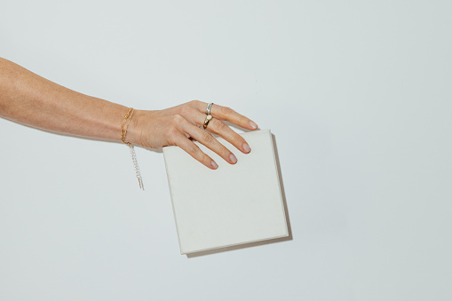 Unrecognizable woman holding a white gift for xmas eve in front of white background.