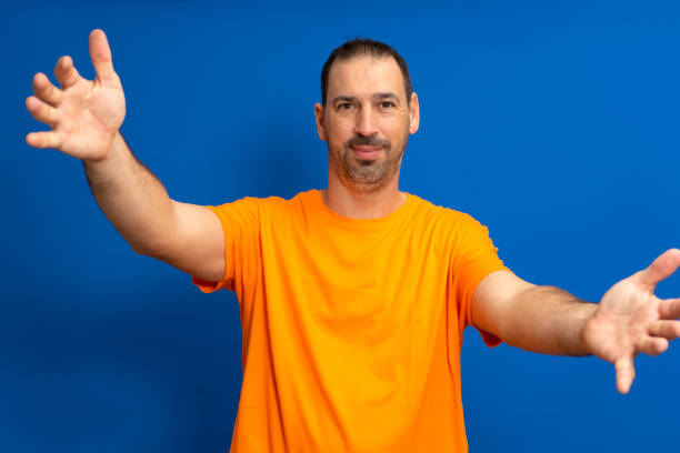 istock Bearded crazy hispanic man smiling cheerfully giving warm, friendly and loving welcome hug, feeling happy and adorable isolated over blue studio background. 1443614049