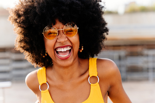 Beautiful young happy african woman with afro curly hairstyle strolling in the city - Cheerful black student portrait outdoors