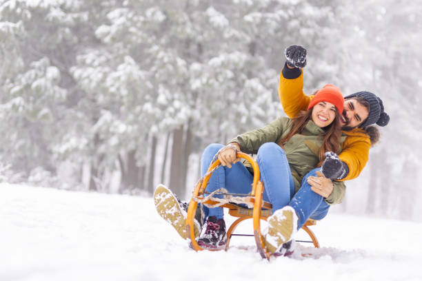 istock Couple sitting on sled and sliding down the hill while on winter vacation 1443624801