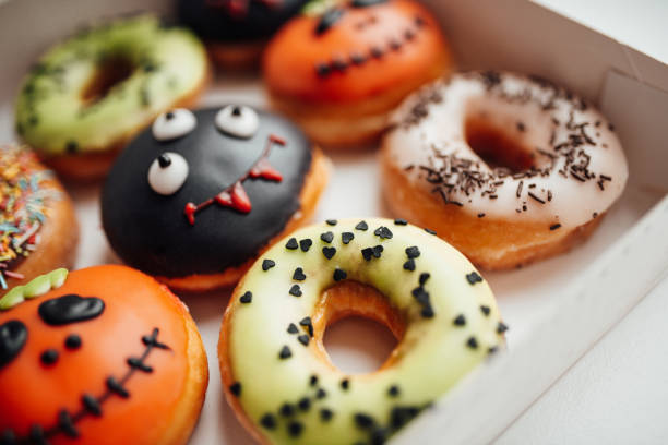 istock Assortment of halloween monsters with funny faces donuts in box at home interior 1443624904