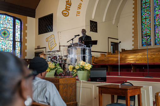 Group of African Americans attending church and listening to a pastor speak.