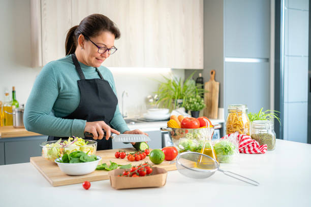 istock Wellbeing: woman preparing healthy salad 1443625713