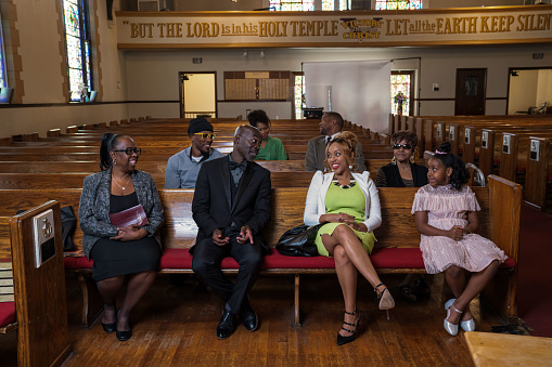 Group of African Americans attending church and listening to a pastor speak.