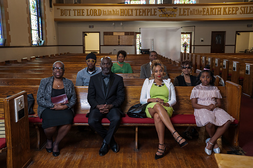 Group of African Americans attending church and listening to a pastor speak.
