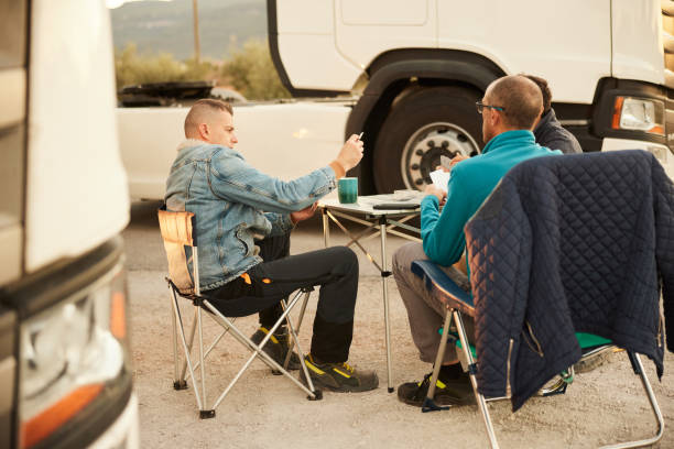 due camionisti maschi che si rilassano su una partita di carte da gioco alla fermata del camion - truck driver truck manual worker semi truck foto e immagini stock