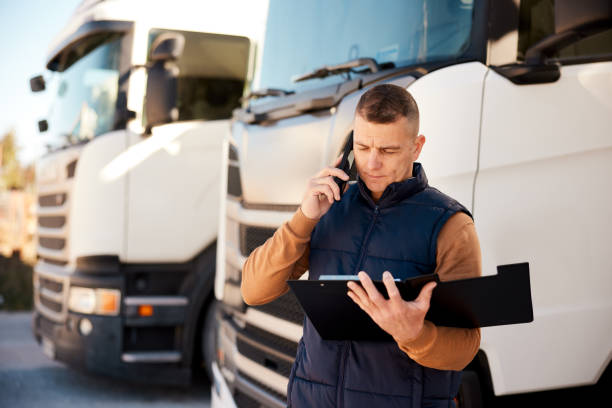 Truck driver with open clipboard folder talking on mobile phone in parking lot stock photo