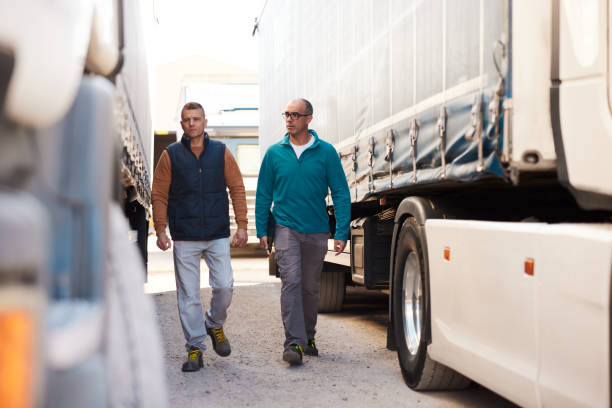 Two truck drivers walking and talking in truck parking lot stock photo