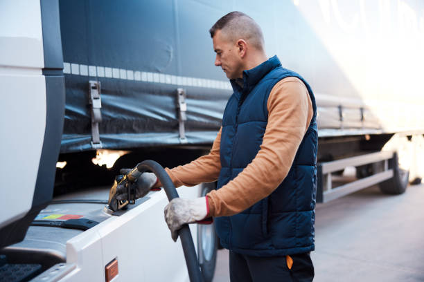 Semi-truck being refueled by mid adult truck driver stock photo