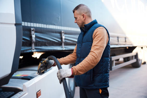 semi-truck being refueled by mid adult truck driver - eastern european imagens e fotografias de stock