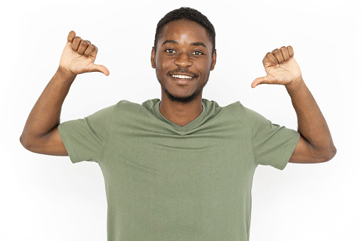 Cheerful young man pointing at himself with thumbs. Male African American model in green T-shirt smiling and pointing at himself with thumbs. Self-assurance, confidence concept