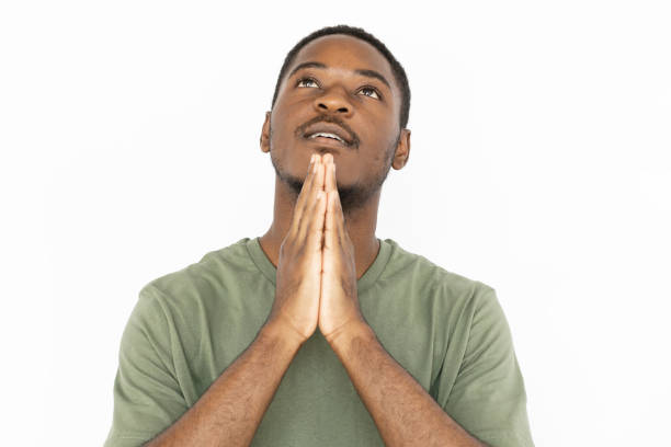 Praying young man with joined hands stock photo