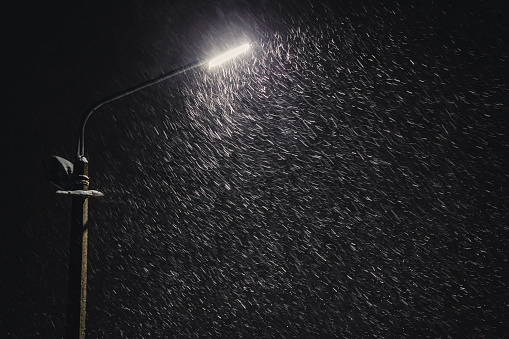 Falling snow on dark background. Snowflake. Winter weather. Climate. Storm. Lantern shine in the dark. Night street