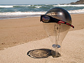 Large lightbulb on the beach wearing sunglasses