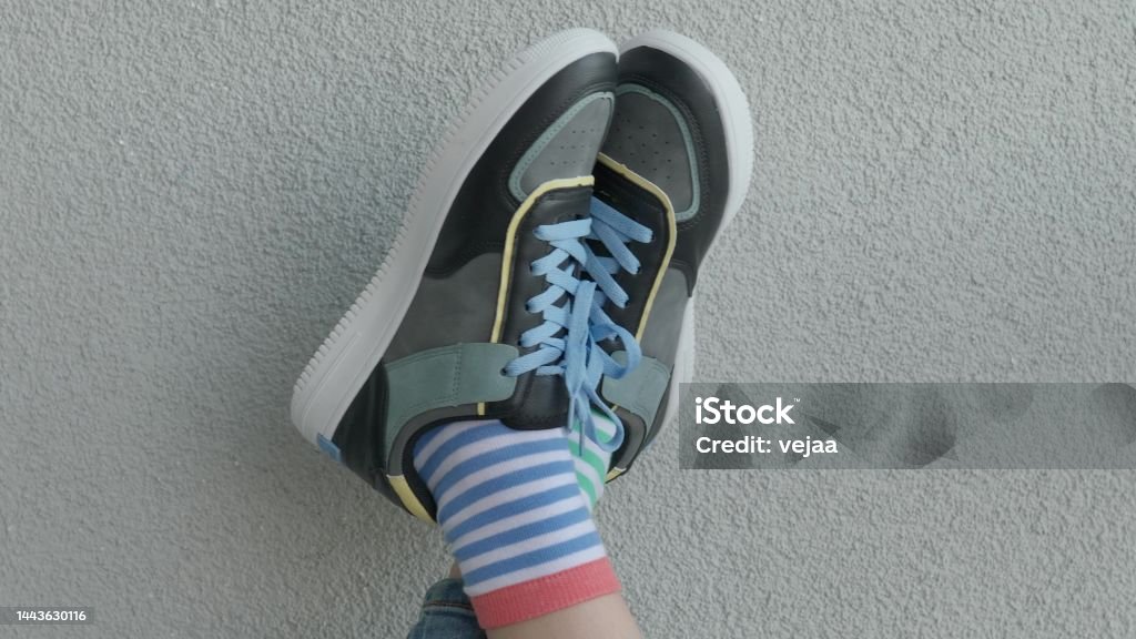 Kid wearing different pair of socks. Child legs up in mismatched socks on gray background. Odd Socks day, Anti-Bullying Week. Down syndrome awareness concept Kid wearing different pair of socks. Legs in mismatched socks on gray background. Odd Socks day, Anti-Bullying Week. Down syndrome awareness concept 4K Resolution Stock Photo
