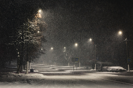 Night street. Blizzard. Falling snow on dark background. Snowflake. Winter weather. Climate. Storm. Lantern shine in the dark
