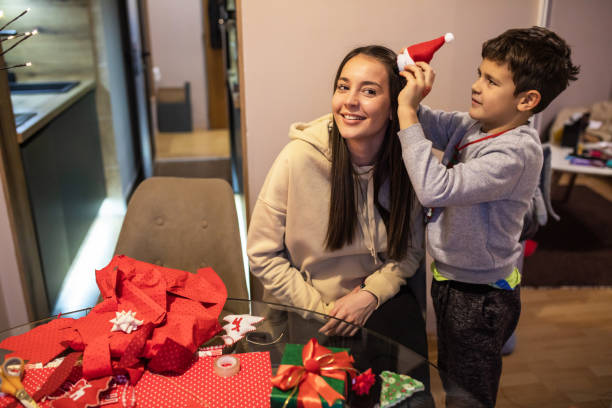 istock A playful boy putting a tiny Santa's hat on his mom's head 1443633565