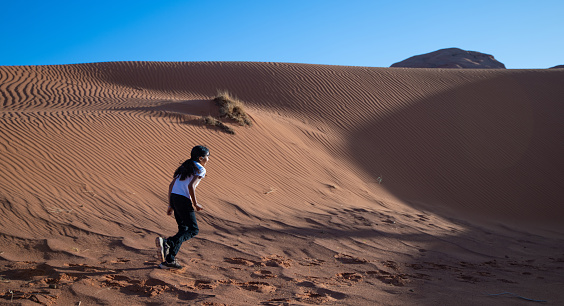 Native american navajo girl running among  the sand dunes of Monument Valley Utah