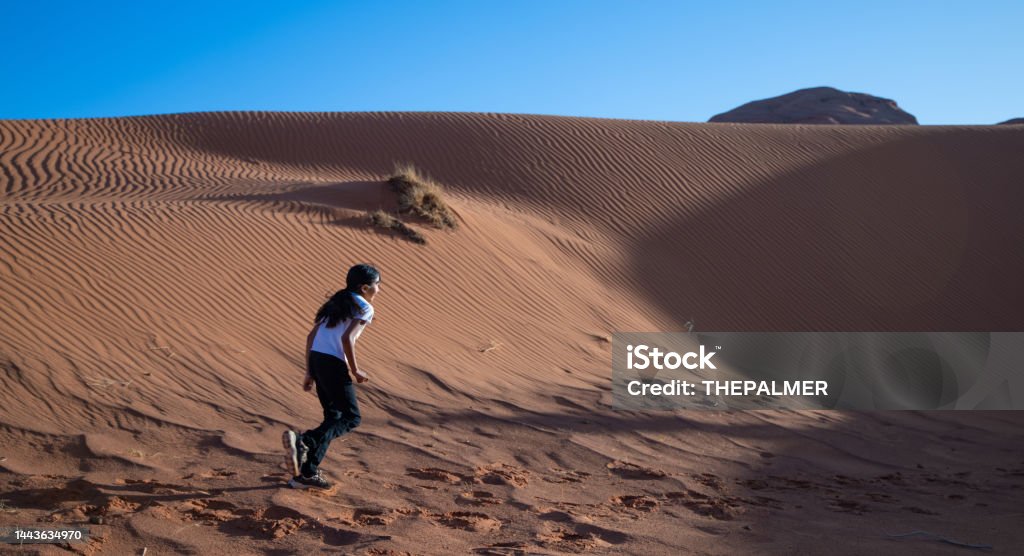 Native american navajo girl running among  the sand dunes of Monument Valley Utah American Culture Stock Photo