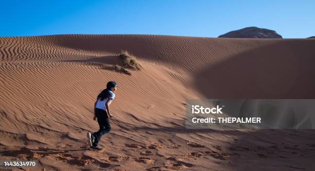 Native American Navajo Girl Running Among The Sand Dunes Of Monument Valley Utah Stock Photo - Download Image Now