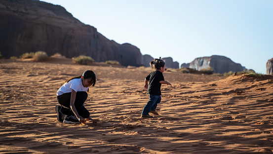 Brother and sister playing on the sand dunes of Monument Valley desert
