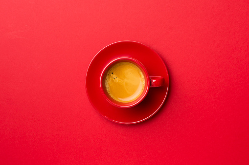 Cup of delicious coffee on color background, top view.