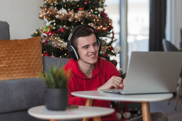 Young man laughing when playing video games via laptop stock photo