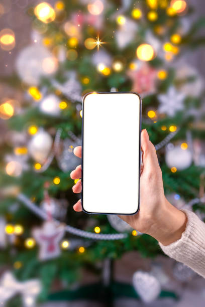 istock Close up smartphone with empty screen mockup on holiday background with Christmas tree 1443641268