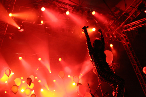 Singer on stage with hand in the air at a concert.