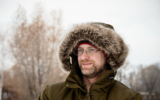A caucasian canadian middle aged man is bundled up in his winter clothes
