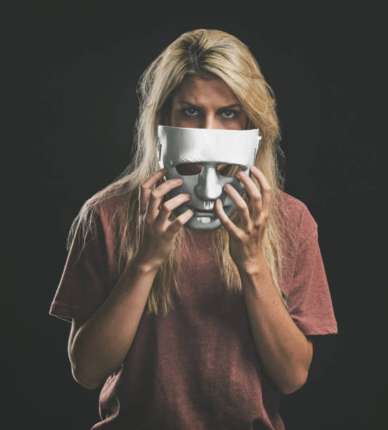 istock Sad portrait and woman with bipolar mask to hide depression struggle with mockup in studio. Depressed girl hiding identity, emotions and mental health disorder with theatre face disguise. 1443653503