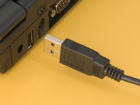 BLACK USB PLUG AND LAPTOP ON YELLOW BACKGROUND 