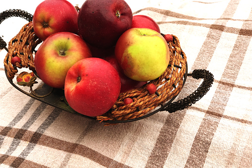 red ripe apples lie in a decorative vessel on the background of a light checkered plaid.
