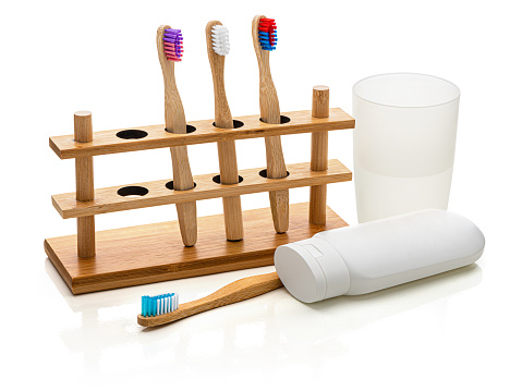 Bamboo toothbrushes in a holder.  
Glass of water and toothpaste. 
Isolated on white.