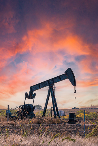 American Oil Pump Jack Producing Oil from The Ground in Kansas at Sunset or Sunrise. Image Taken Near the Town of Hays, Kansas, USA\n\nUse of Crude Oil Is a Controversial Topic in The American Election Cycle and Among Financial Circles.
