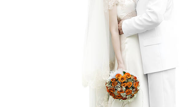 Bride and groom kissing in white with a colorful bouquet  stock photo