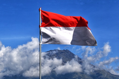 Indonesian flag with clouds and mountain peak in the background